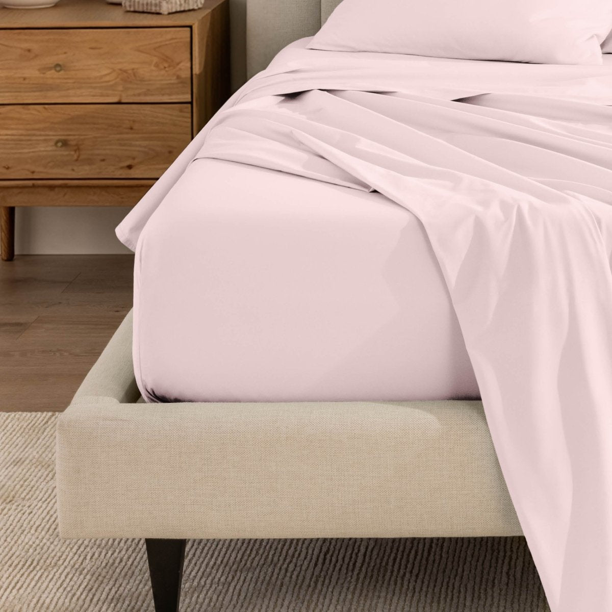 Top sheet and a matching fitted sheet on a bed with a beige bed frame
