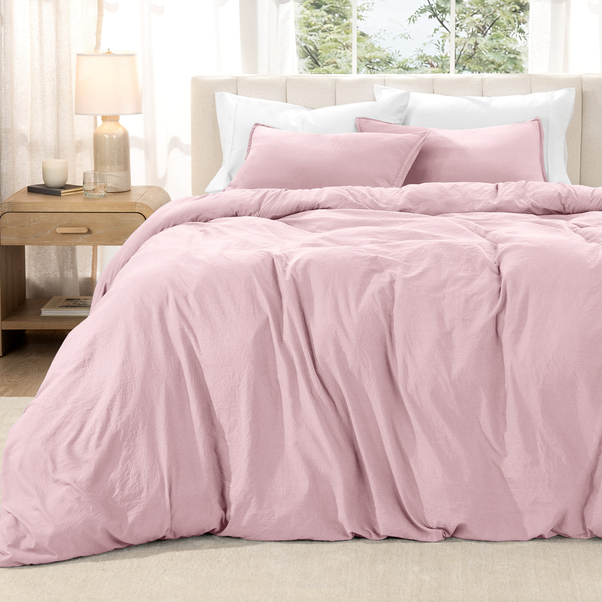 Washed duvet set on a bed in a bright bedroom with a lamp and window.