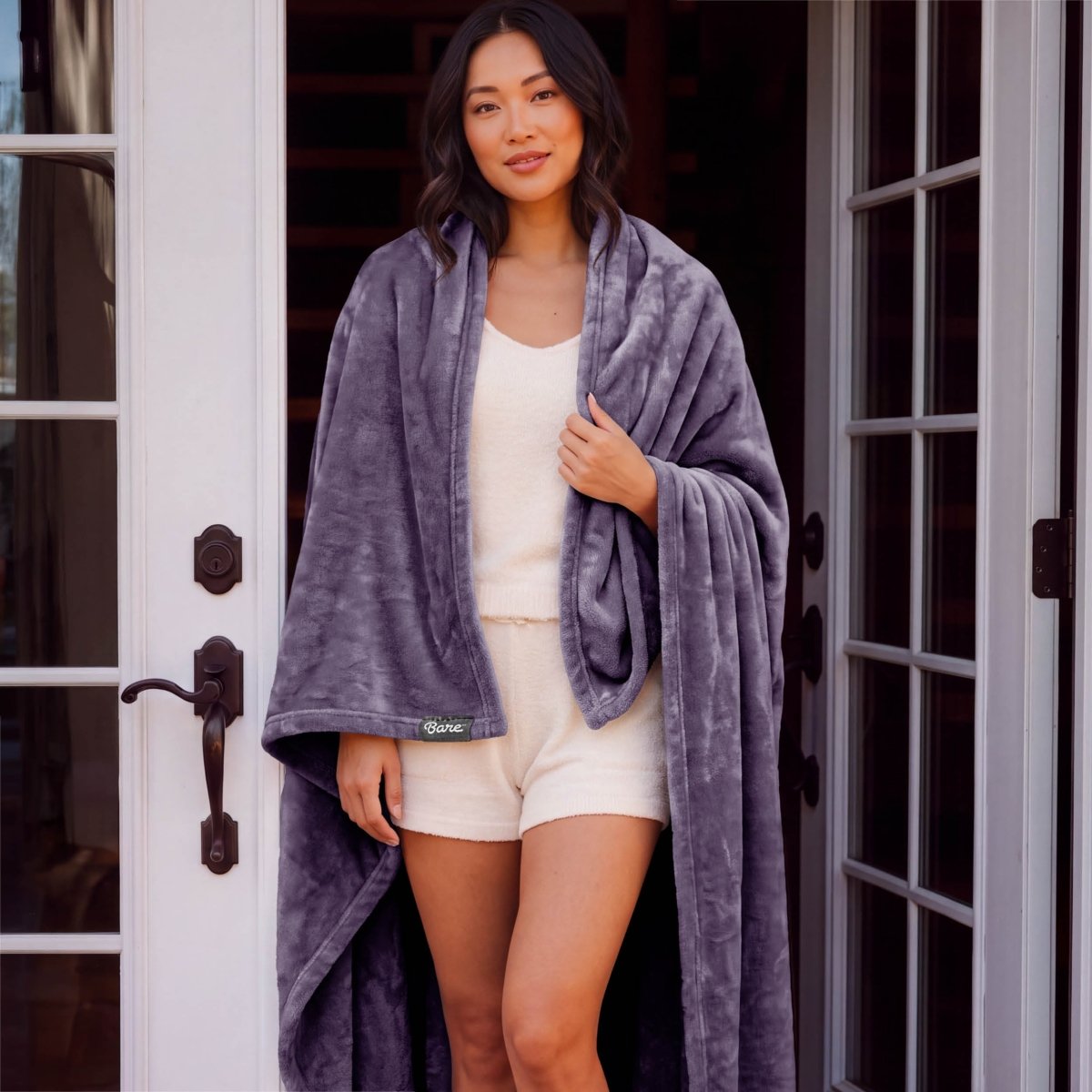 A woman standing with a microplush blanket wrapped around her