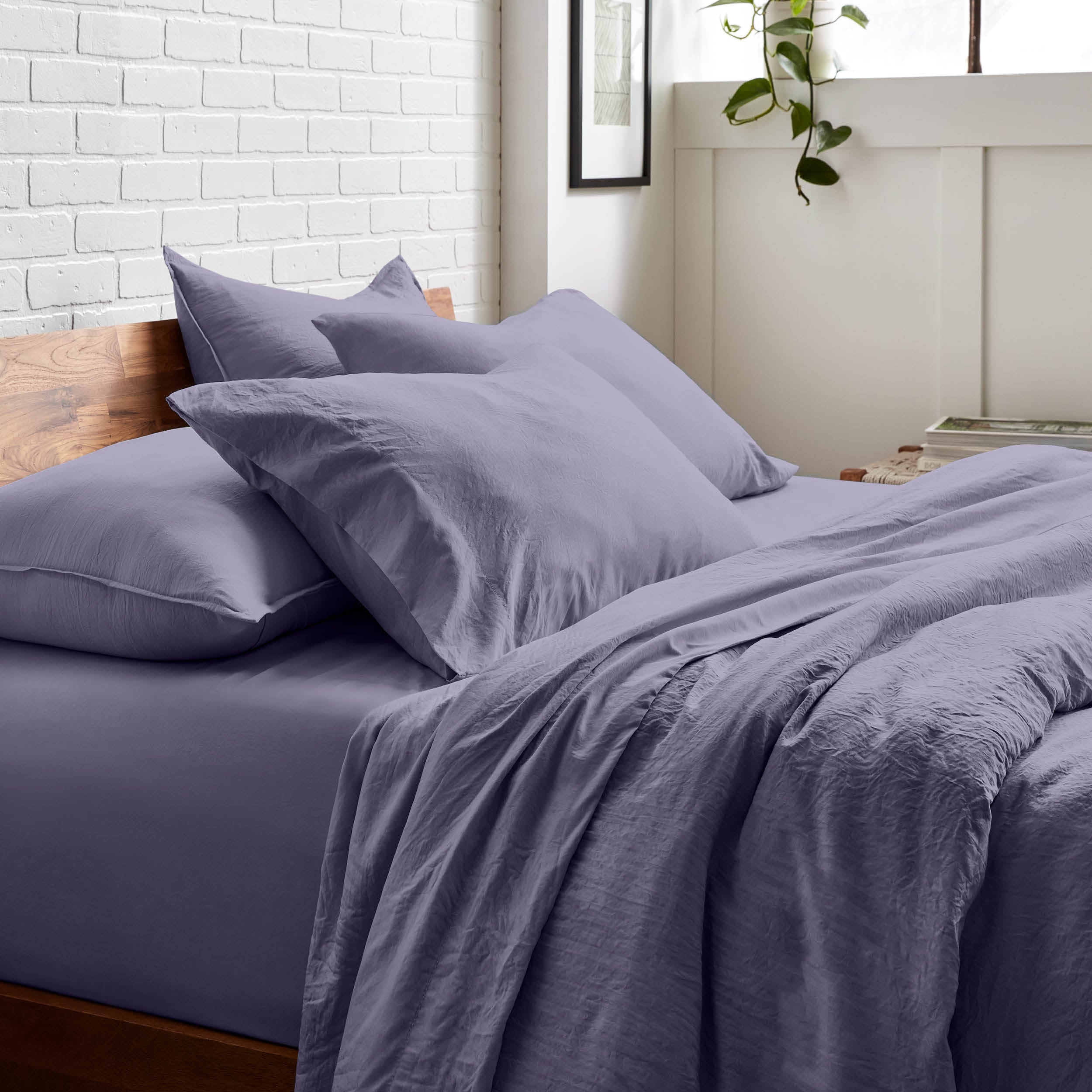 Bedding set on a bed with a white brick wall and window in the background