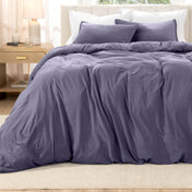Bed with washed bedding and white pillows in a bright room