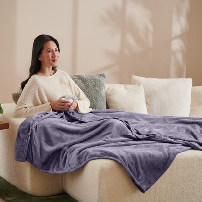 A woman sitting on a couch with a microplush blanket on her lap