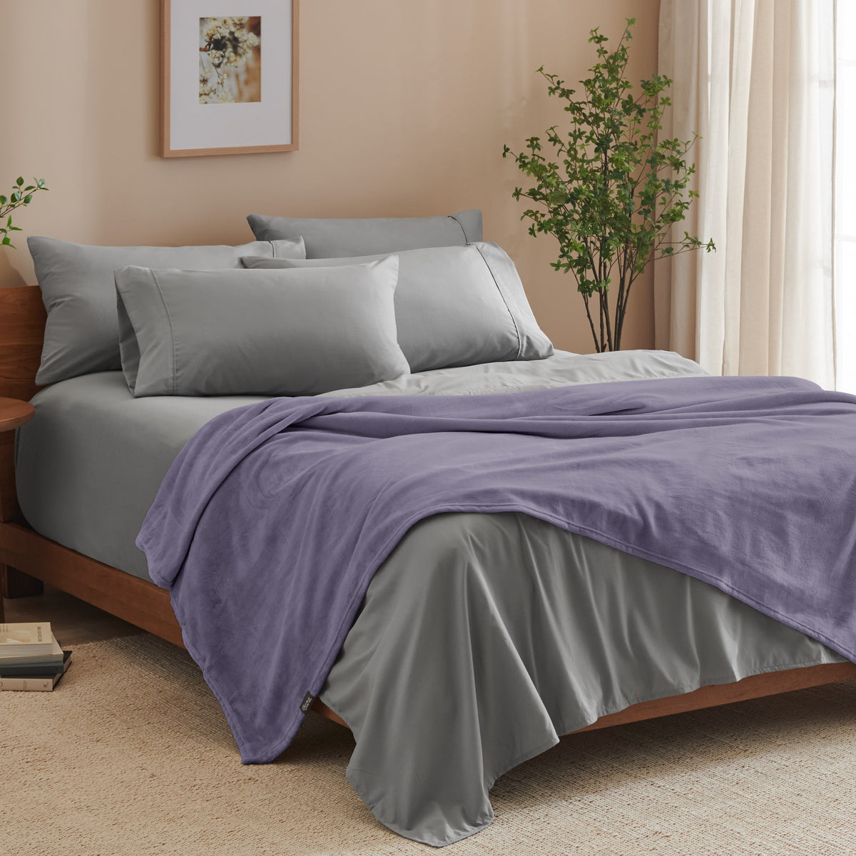 A bed made with grey sheets and a microplush blanket