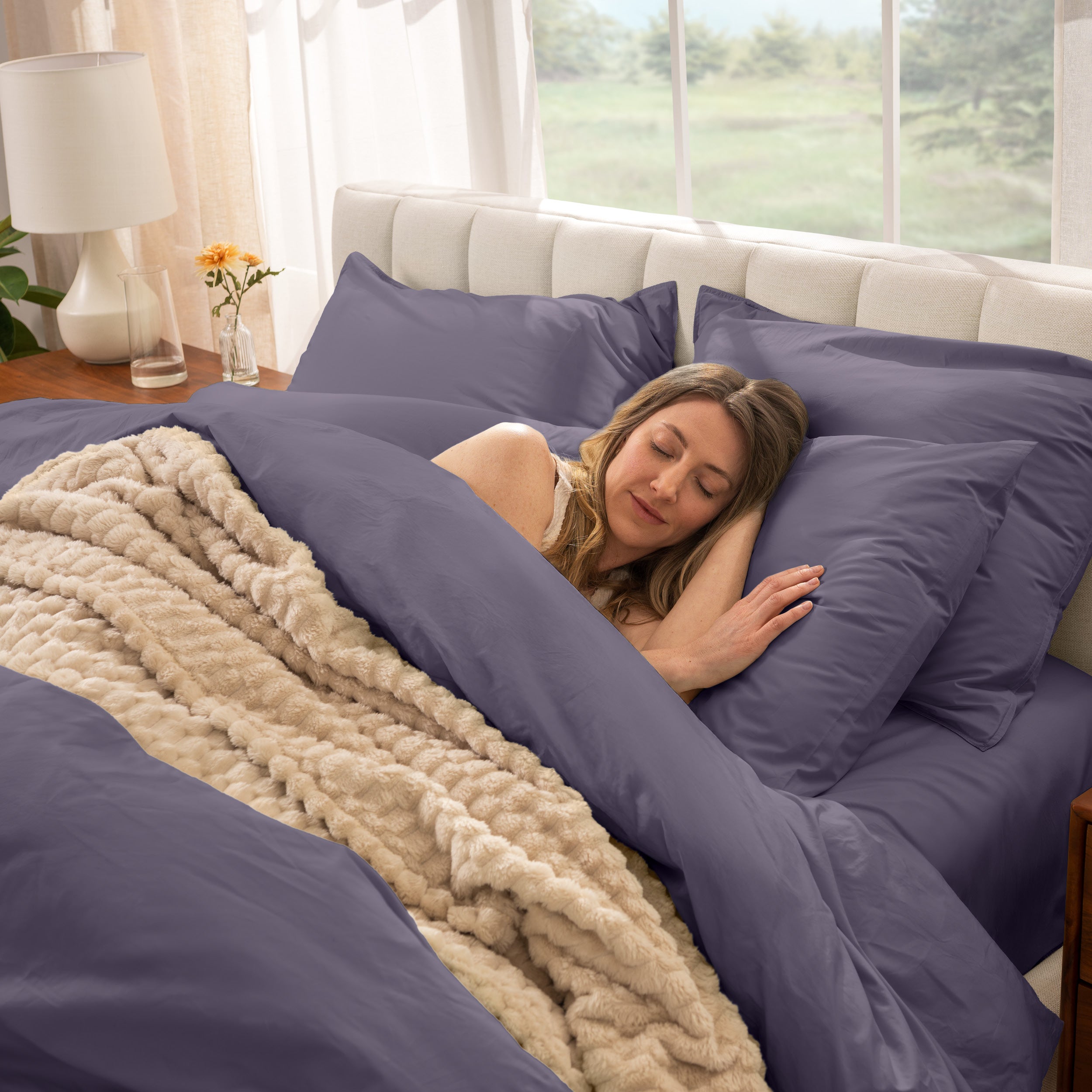 Woman sleeping in a bed with percale bedding and beige blanket
