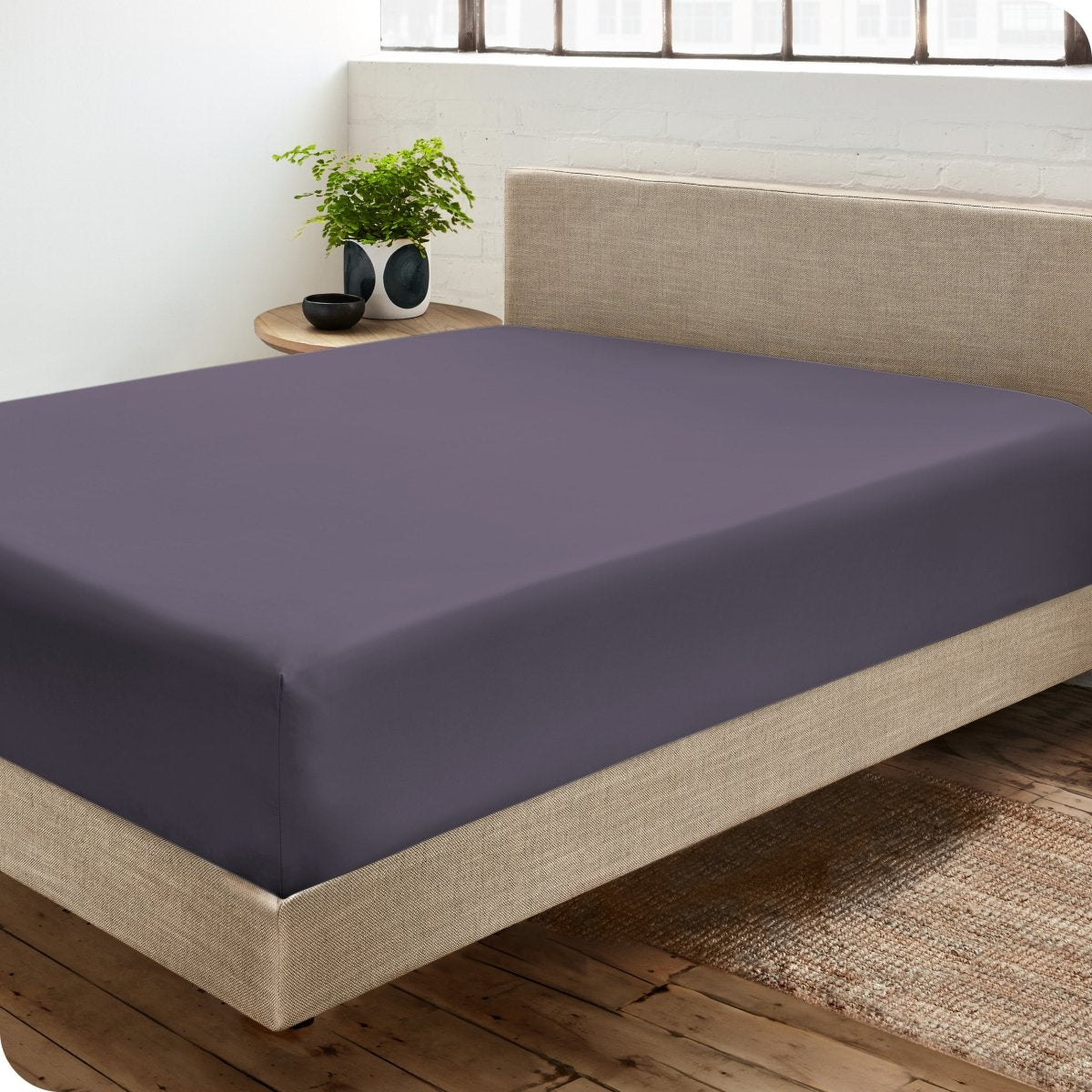 Diagonal view of modern bedroom with a sateen fitted sheet on the bed