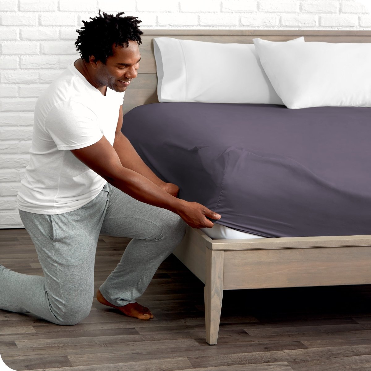 Man putting the corner of fitted sheet on a mattress