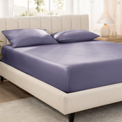 Bed with fitted sheet and pillowcases in a bright room.