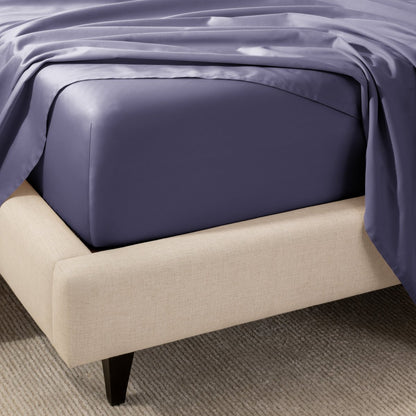 A close-up of the corner of a bed with a fitted sheet and matching flat sheet.