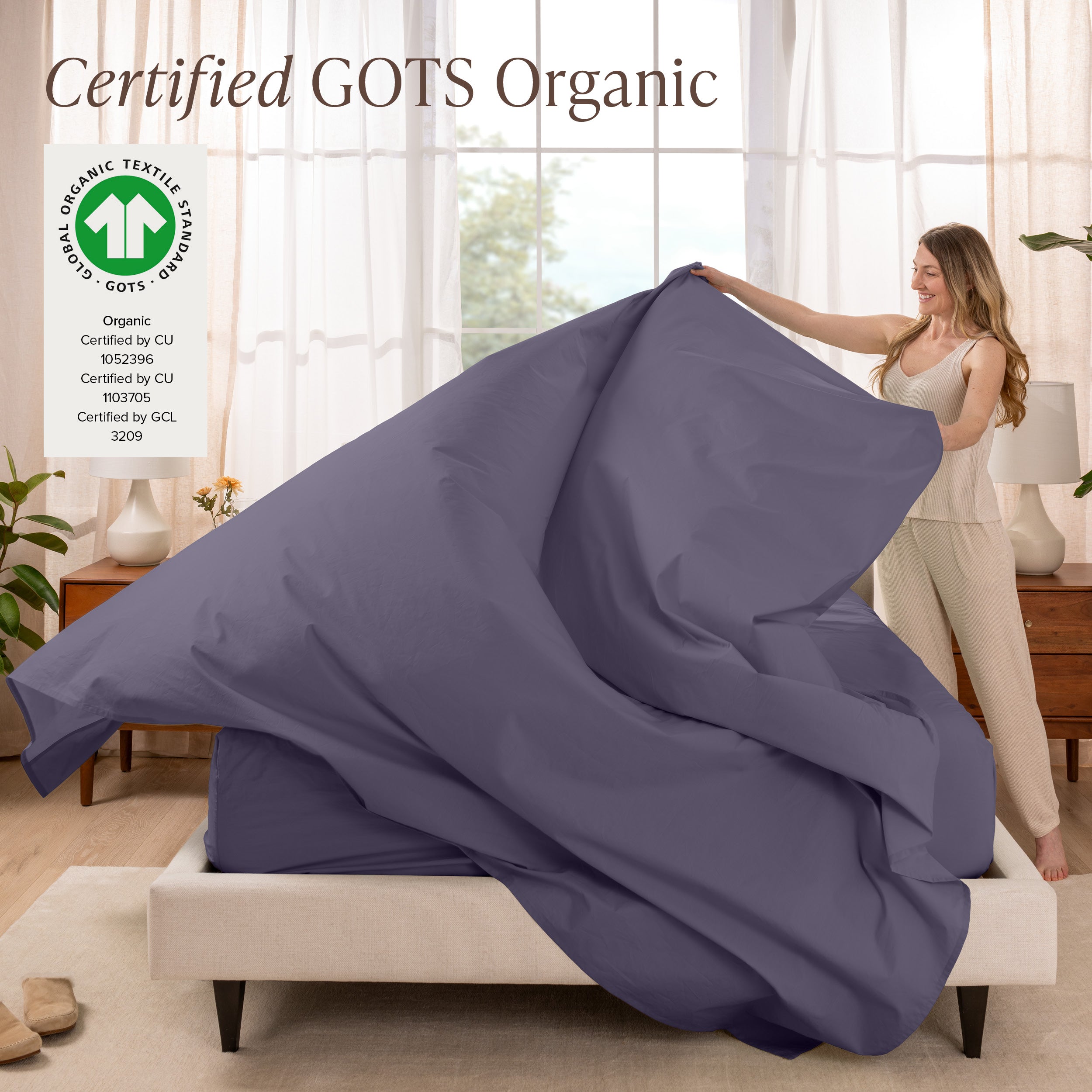 A woman is making a bed with organic cotton percale sheets