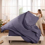 Woman putting a sheet set on a bed in a bright bedroom.