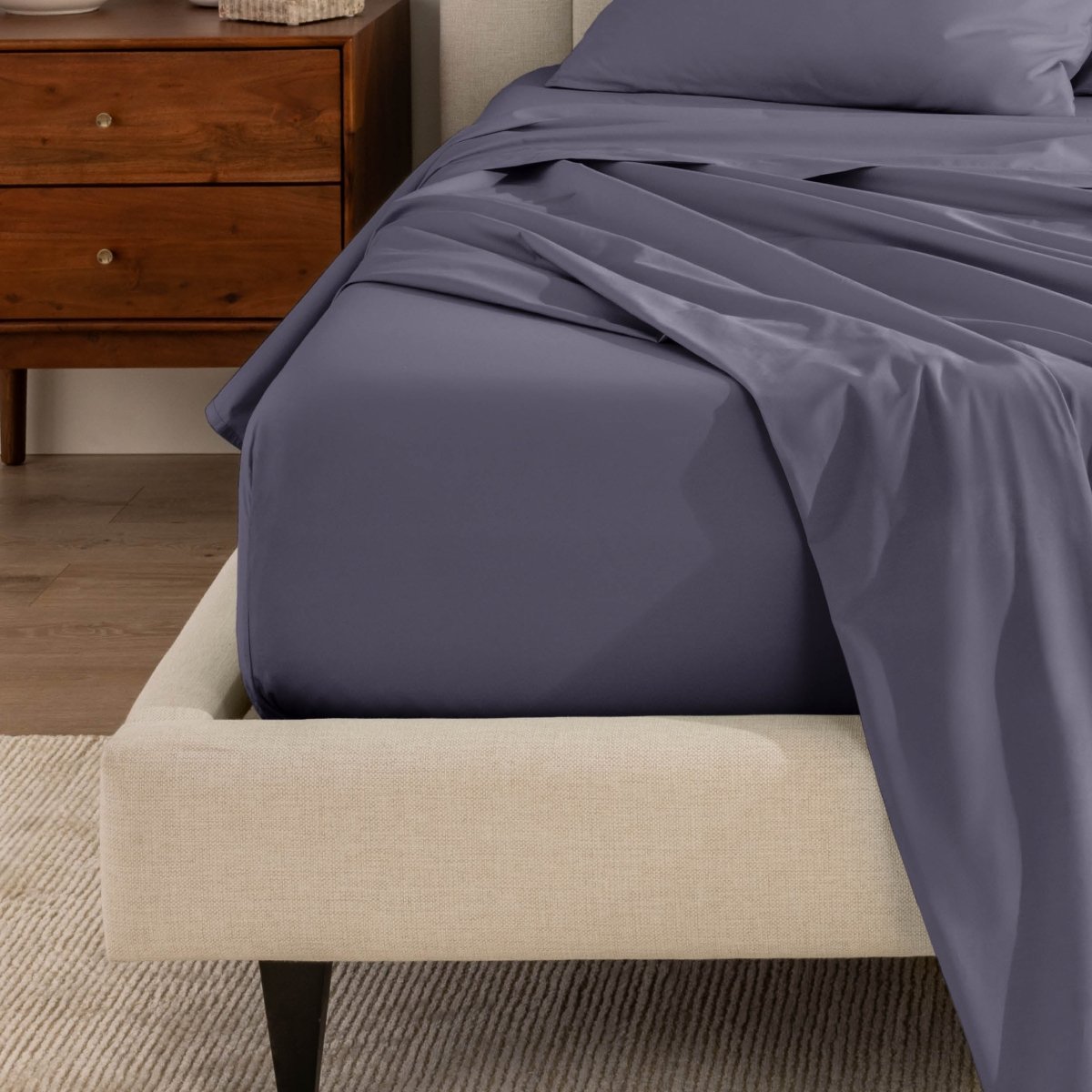Top sheet and a matching fitted sheet on a bed with a beige bed frame