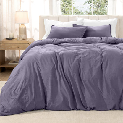Washed duvet set on a bed in a bright bedroom with a lamp and window.