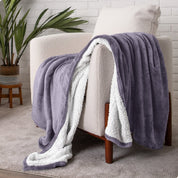 Bed with grey sheets and a sherpa blanket