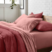 Side view of a bed made with a fitted sheet, pillowcases, and top sheet folded down part way over the duvet cover