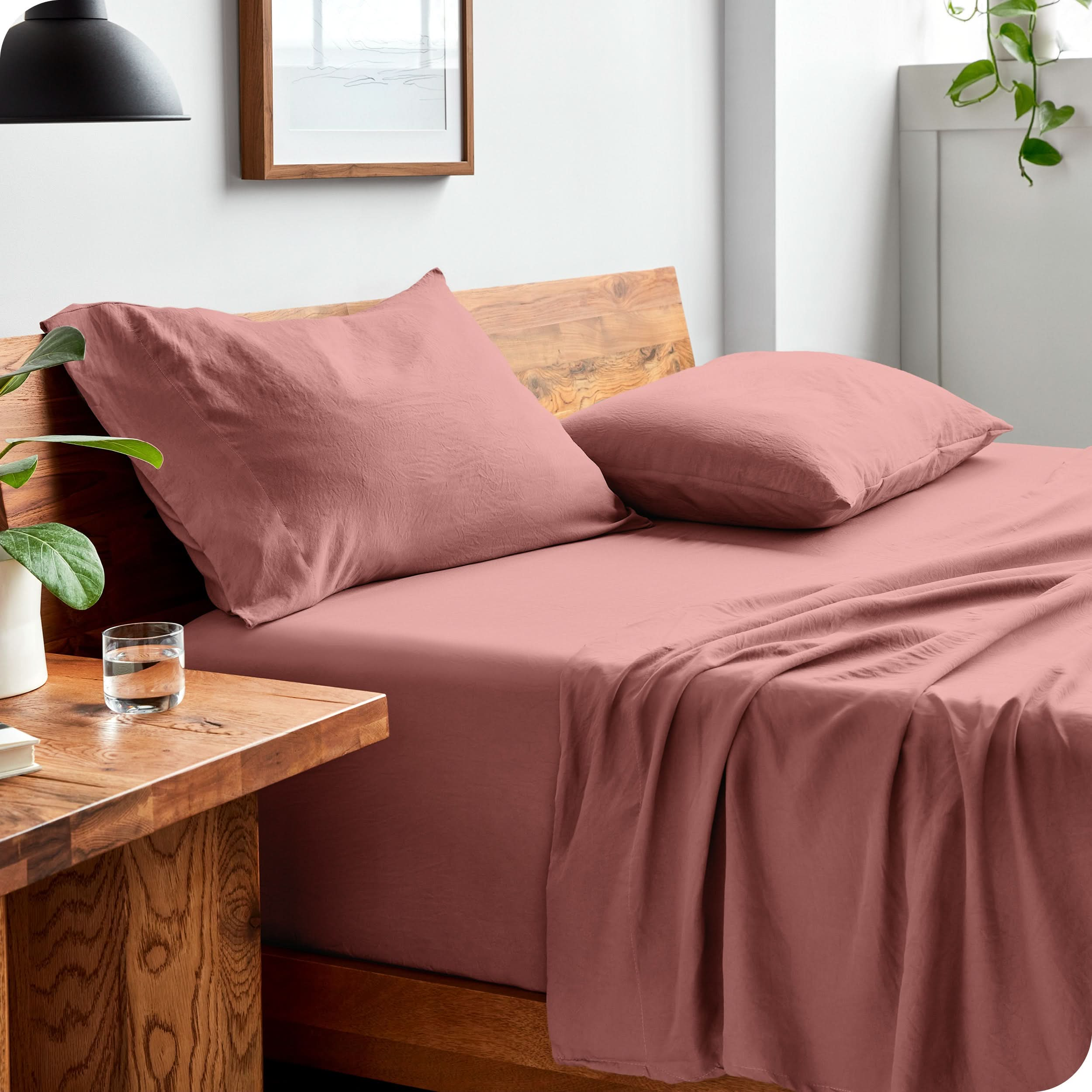 Side view of a bed made with a fitted sheet, pillowcases, and top sheet