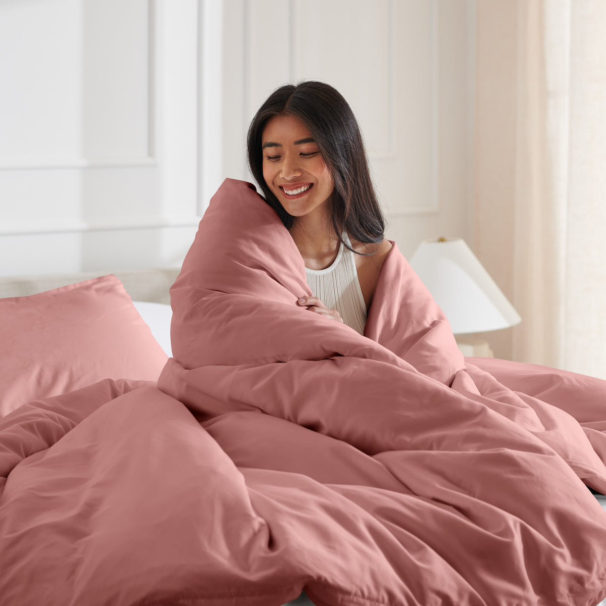 Woman smiling under duvet cover set in a bedroom setting