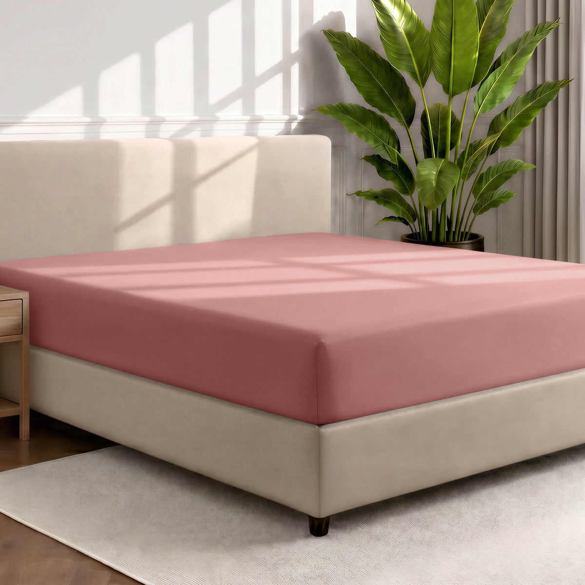 Bed with a fitted sheet in a room with a large plant and rug
