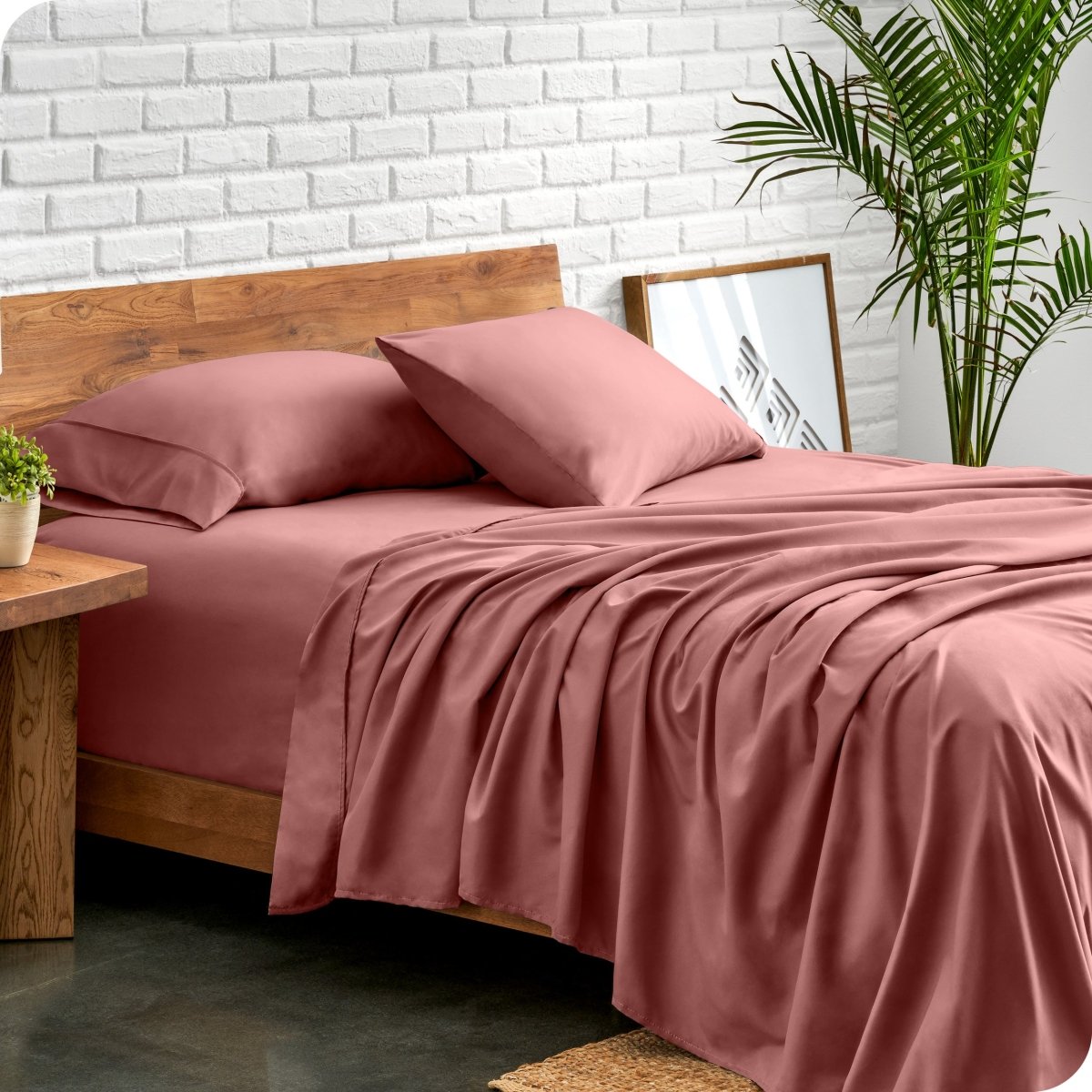 Bed with microfiber sheets against a white brick wall