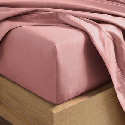 Close up of the corner of a mattress with a fitted sheet and flat sheet on it