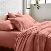 Bedding set on a bed with a white brick wall and window in the background