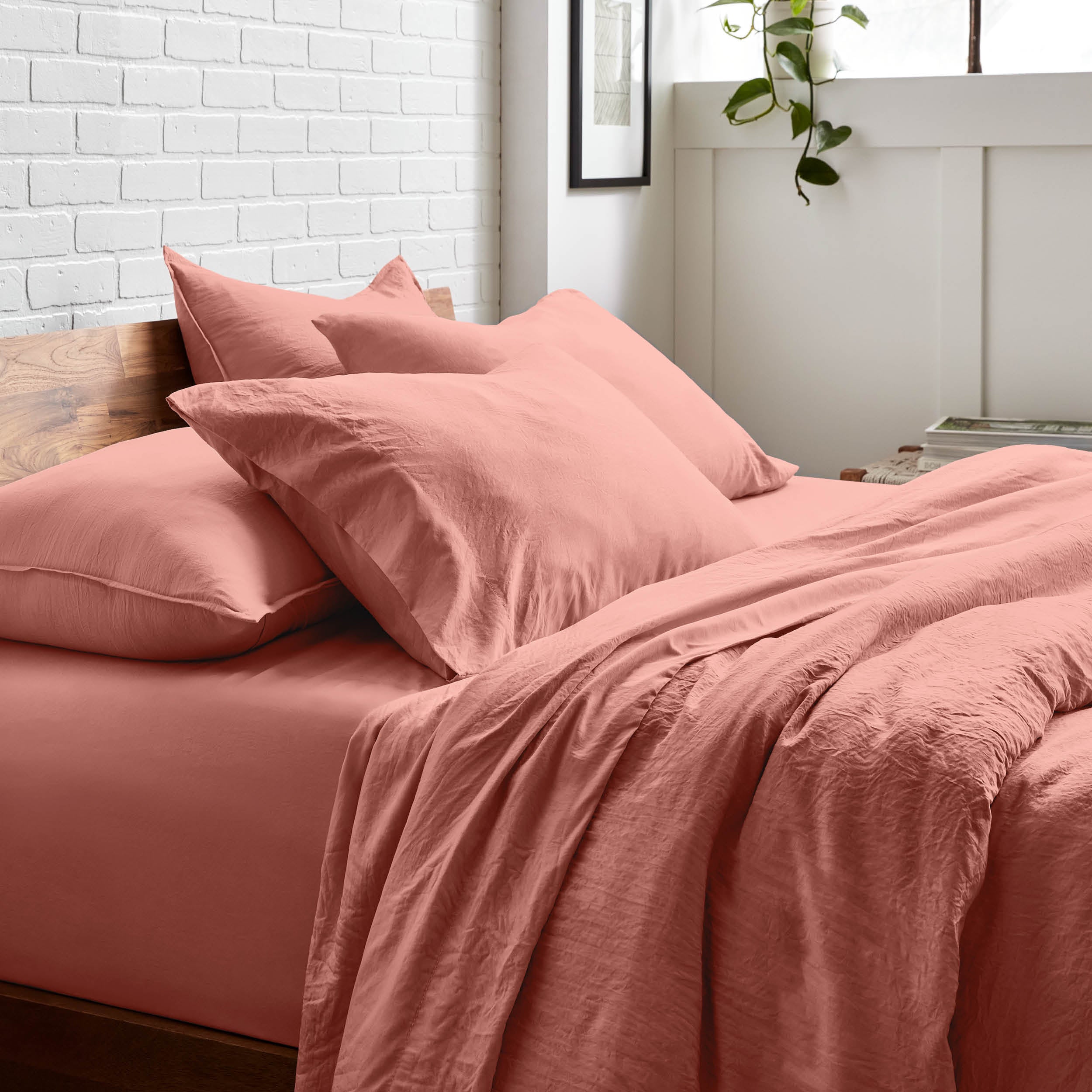 Bedding set on a bed with a white brick wall and window in the background