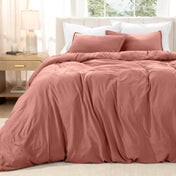 Bed with washed bedding and white pillows in a bright room
