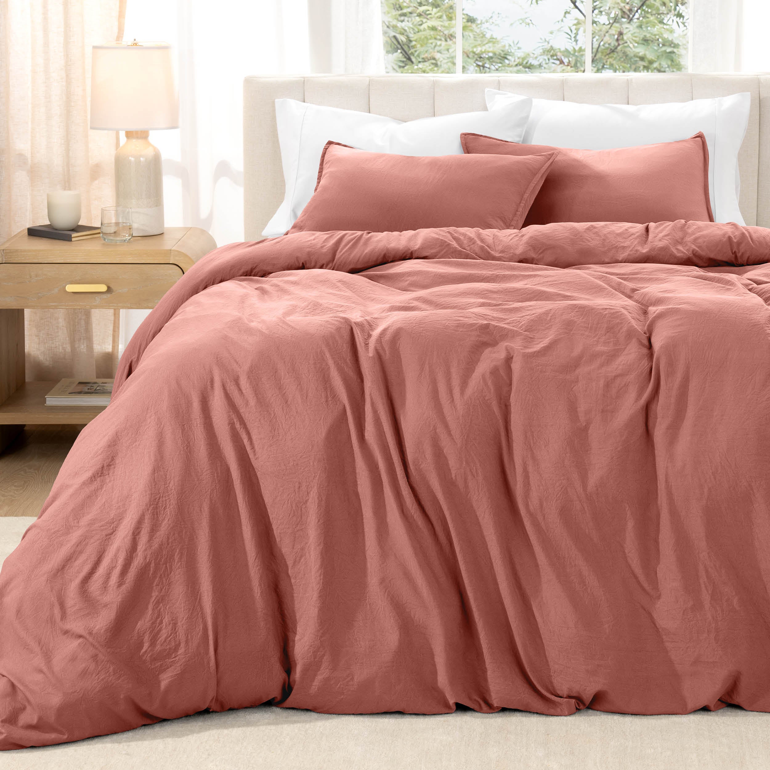 Bed with washed bedding and white pillows in a bright room