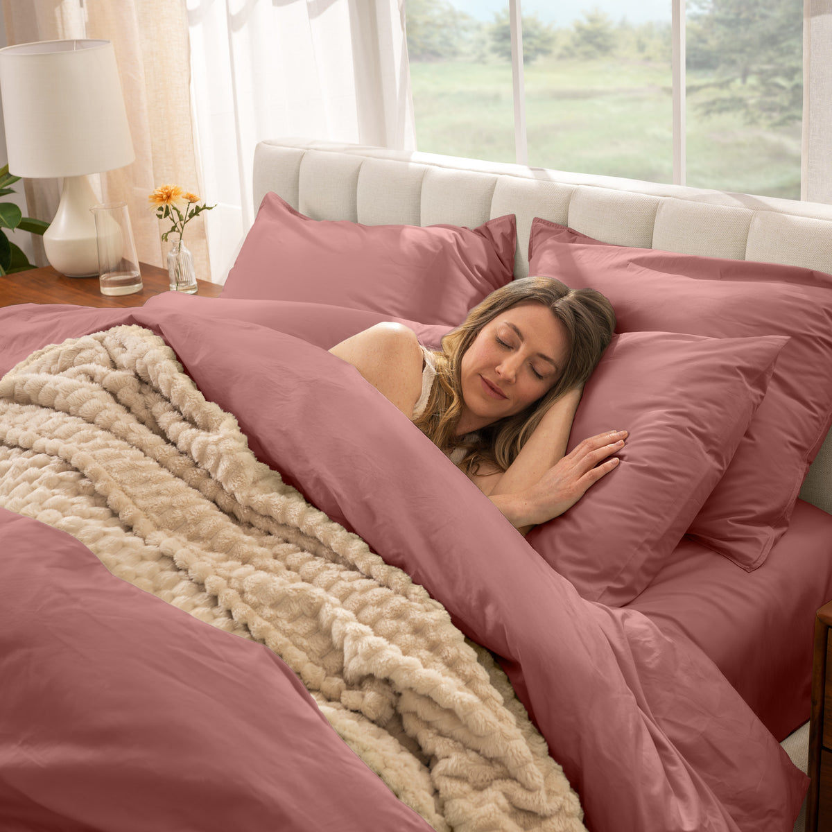 Woman sleeping in a bed with percale bedding and beige blanket
