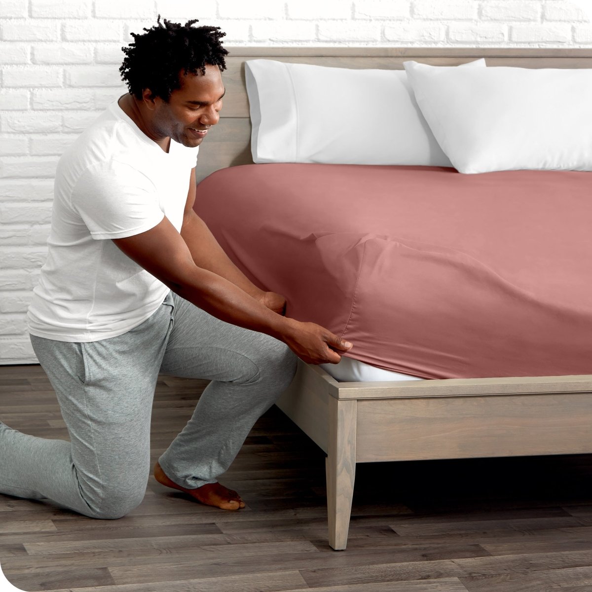 Man putting the corner of fitted sheet on a mattress