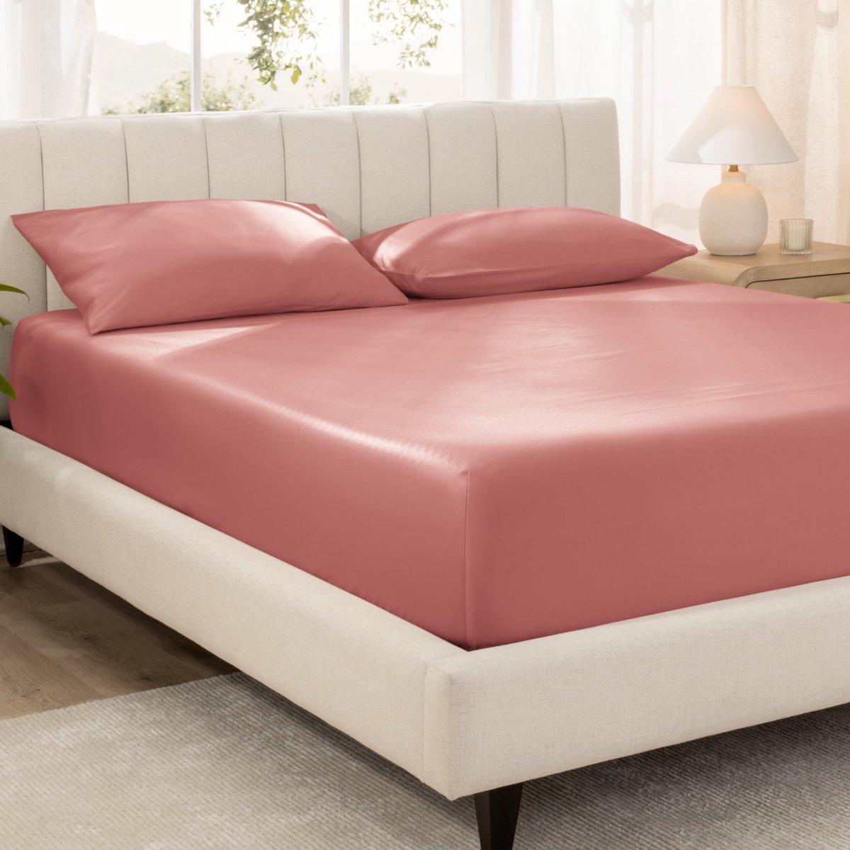 Bed with fitted sheet and pillowcases in a bright room.