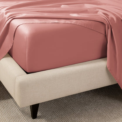 A close-up of the corner of a bed with a fitted sheet and matching flat sheet.