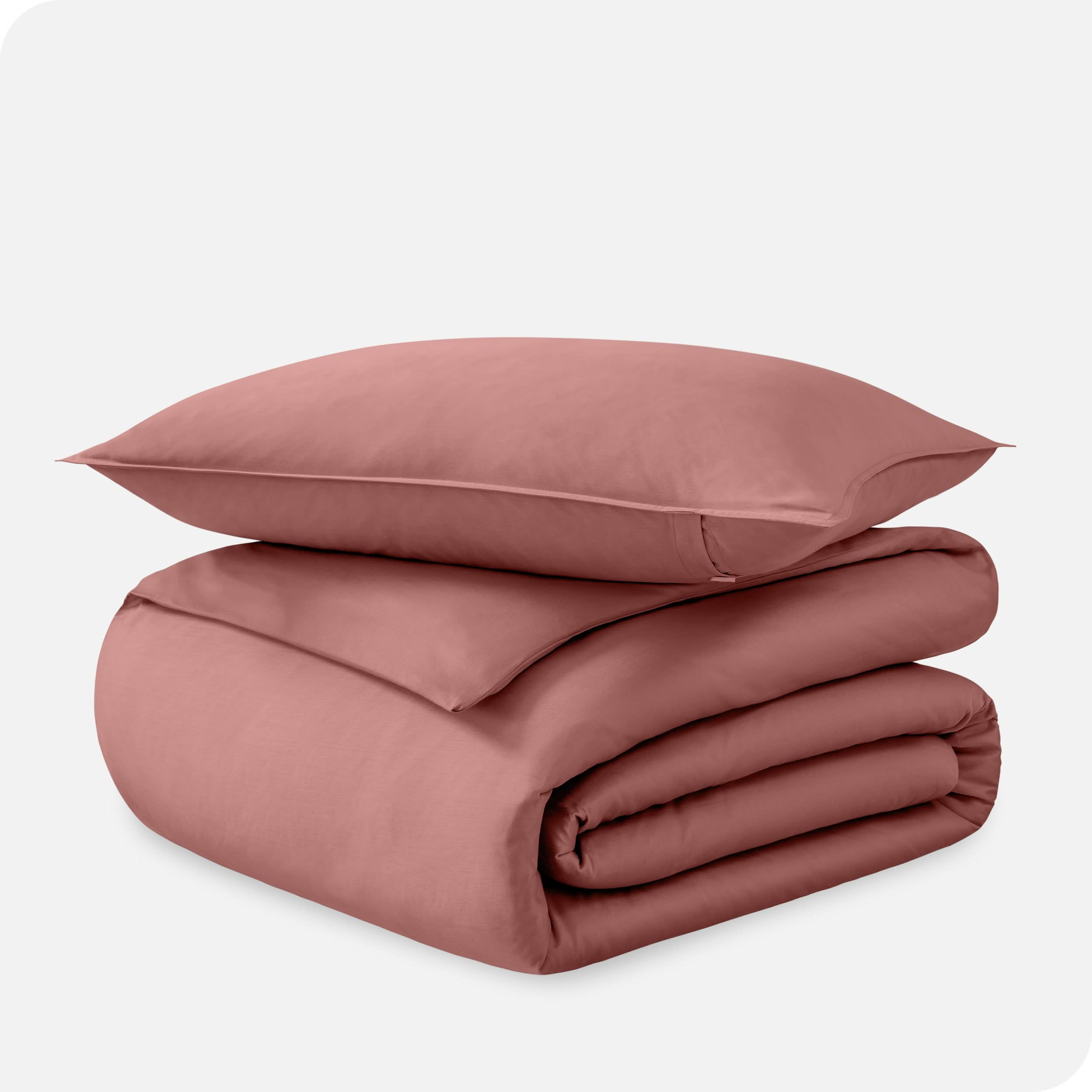 A folded organic sateen duvet cover with a pillow on top.