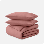 A folded organic sateen duvet cover with two pillows on top.
