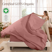 A woman is making a bed with organic cotton percale sheets