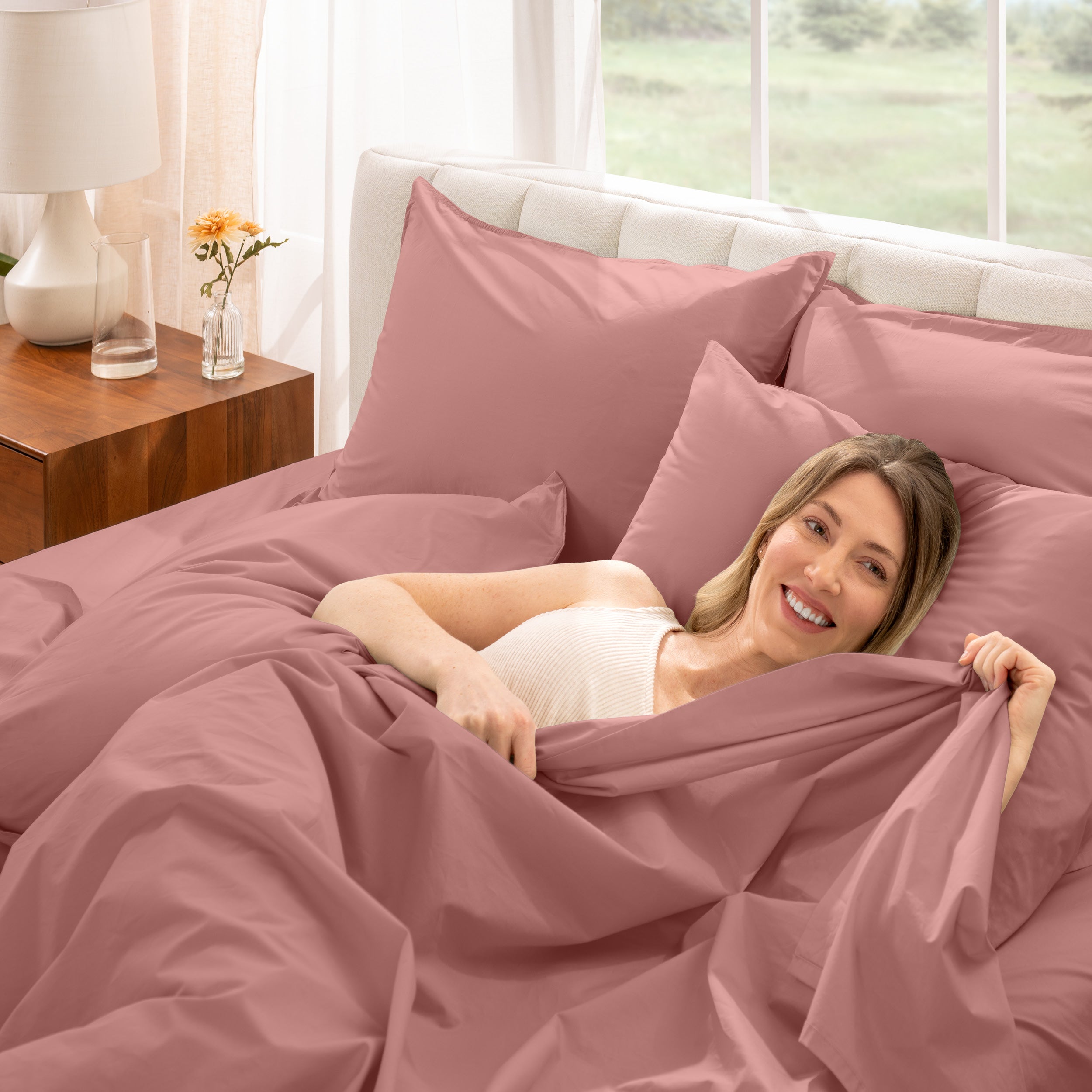 A woman is lying on a bed make with percale sheets and pillowcases