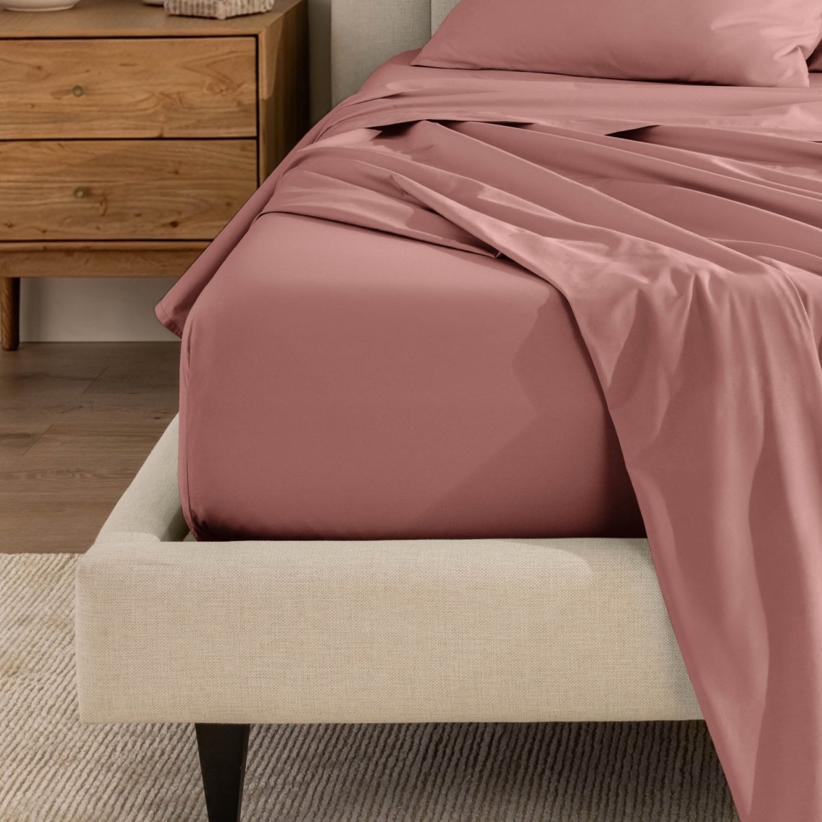 Top sheet and a matching fitted sheet on a bed with a beige bed frame
