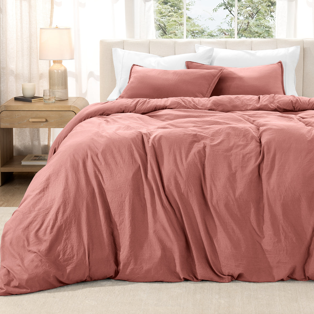 Washed duvet set on a bed in a bright bedroom with a lamp and window.