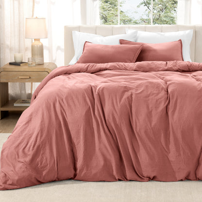 Washed duvet set on a bed in a bright bedroom with a lamp and window.