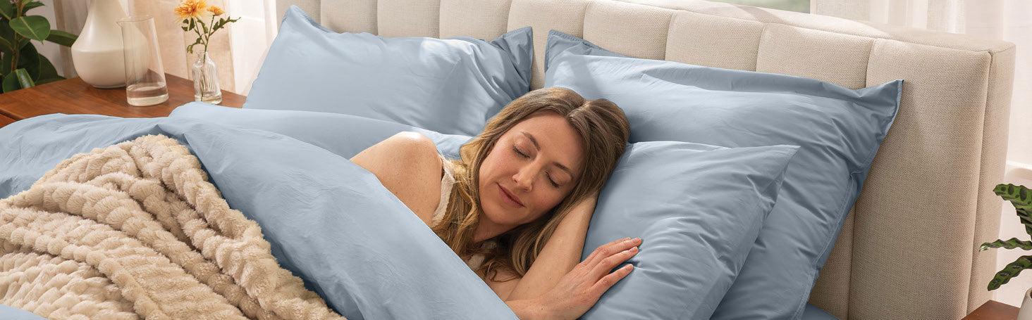 woman sleeping on a dusty blue duvet covered bed