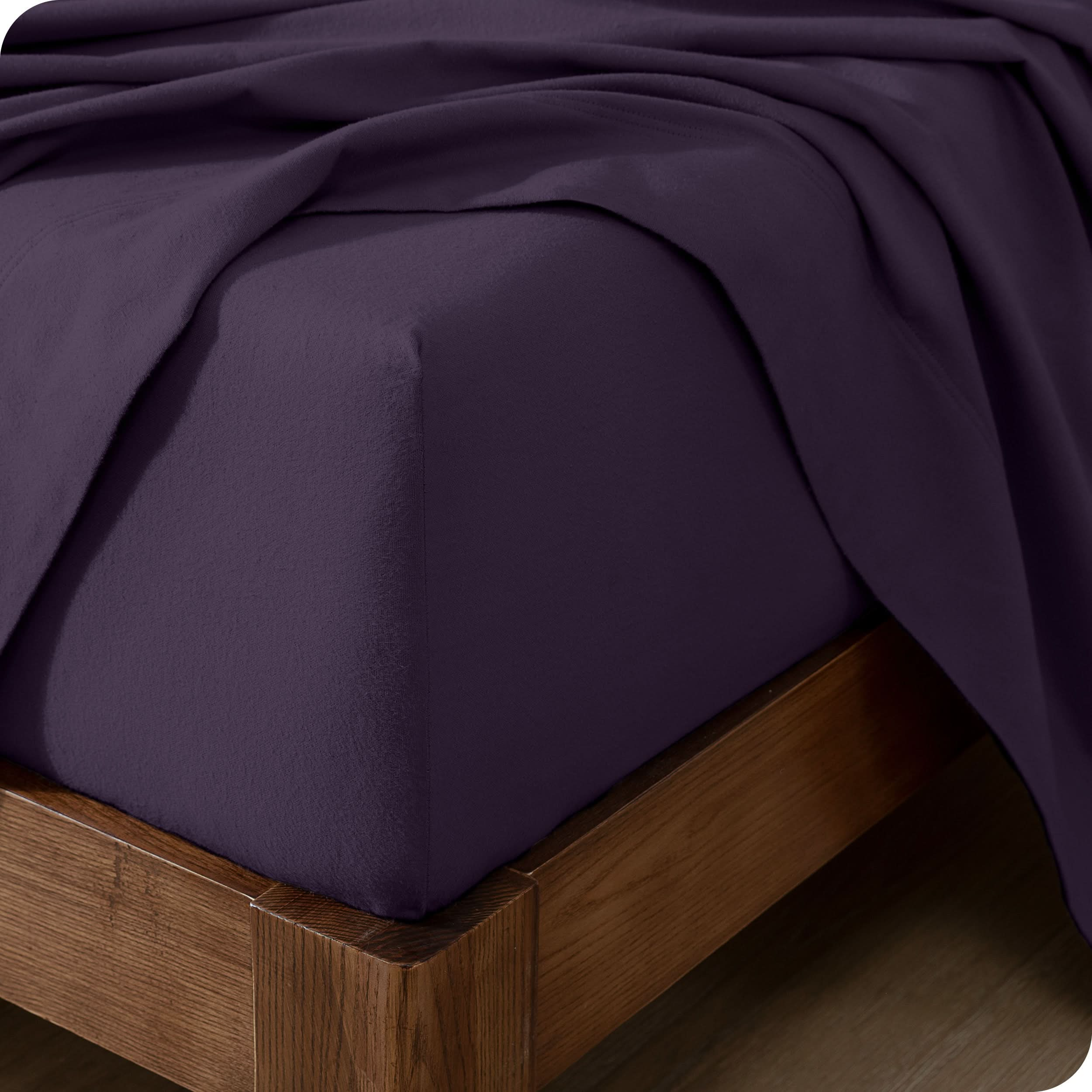 Close up of the corner of a mattress with a flannel fitted sheet and flat sheet on it