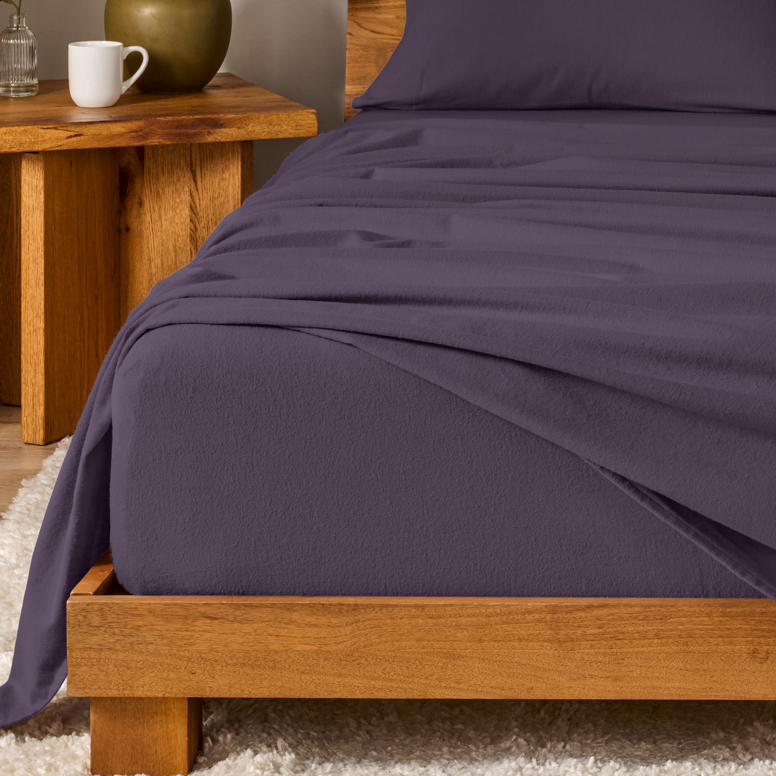 Bed with flannel bedding and wooden headboard and nightstand next to it.