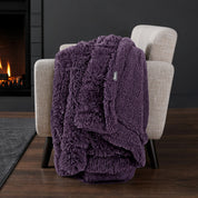 Sherpa blanket draped over an armchair in front of a fireplace.