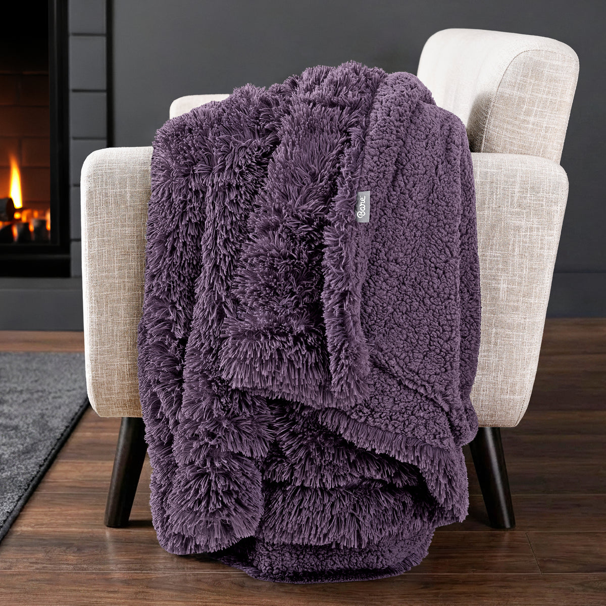 Sherpa blanket draped over an armchair in front of a fireplace.