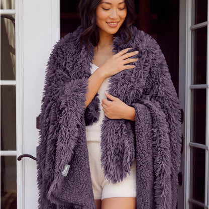 A woman standing with a shaggy blanket wrapped around her