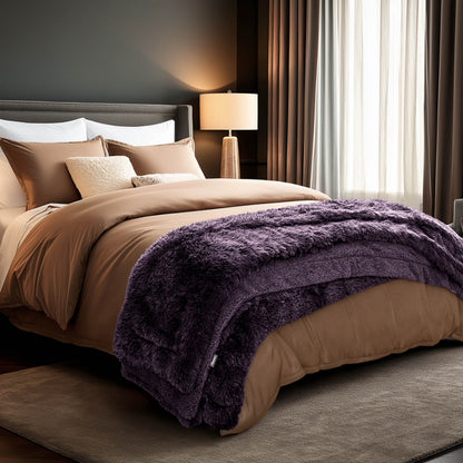 A shaggy faux fur blanket at the end of a bed