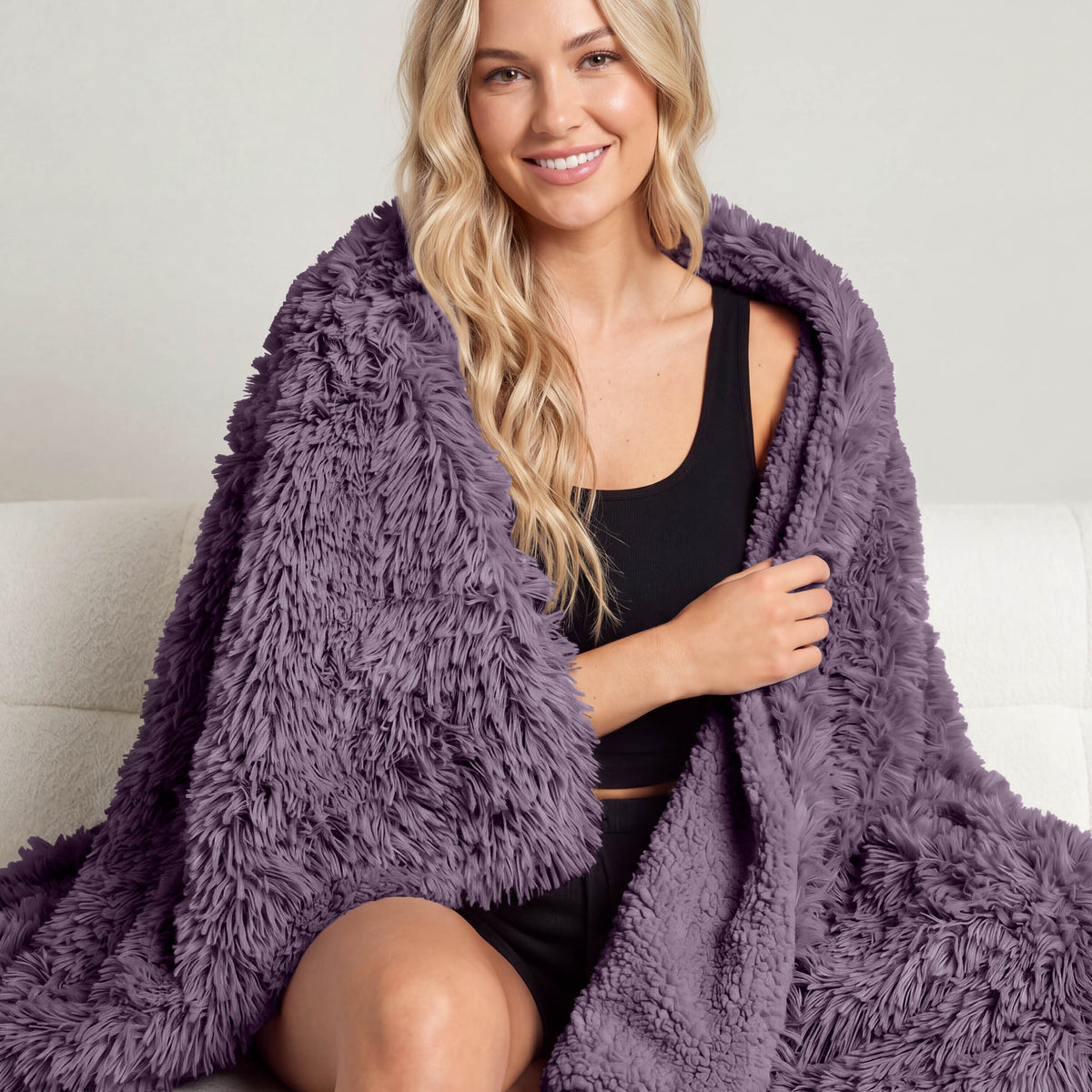 A woman sitting with a shaggy blanket wrapped around her