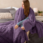 Fluffy blanket draped over a woman sitting on the end of a bed