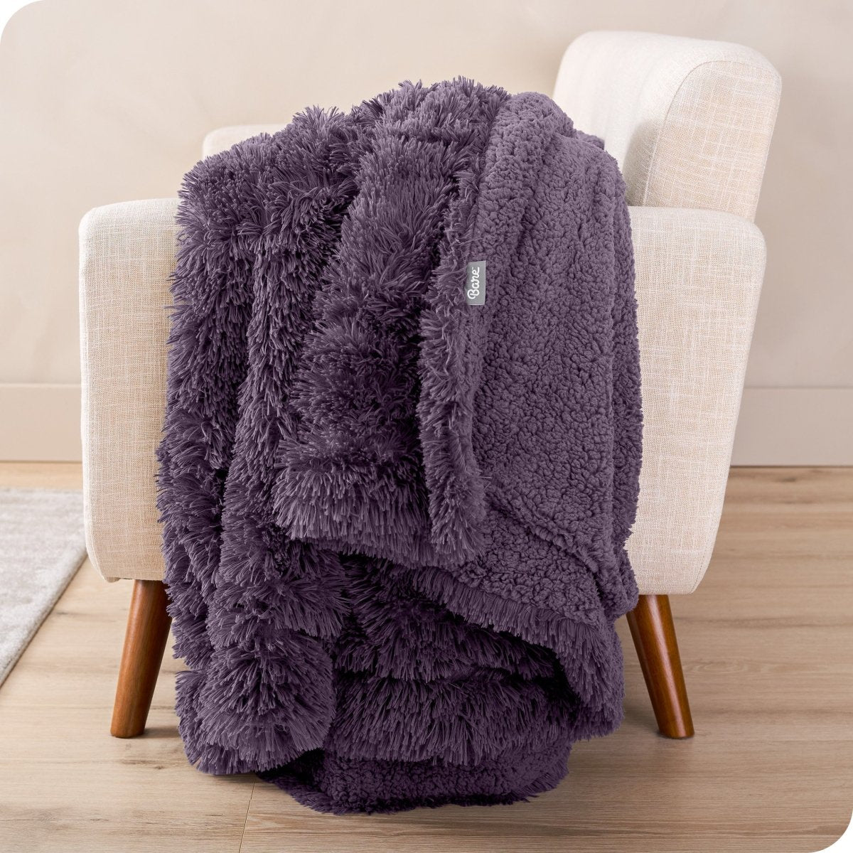 A shaggy faux fur blanket draped over the arm of a chair