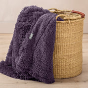 A blanket hanging over the edge of a wicker basket