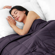 Woman sleeping peacefully under a weighted blanket with white pillows